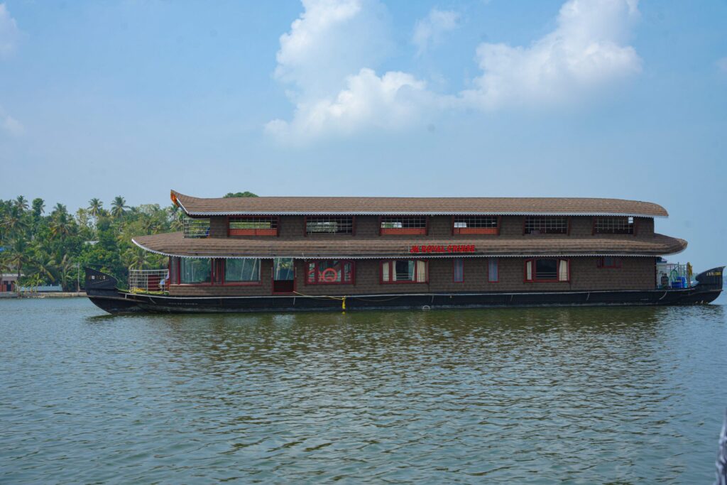 JK Royal Cruise houseboat with 'Royal Cruise' signage on Ashtamudi Lake